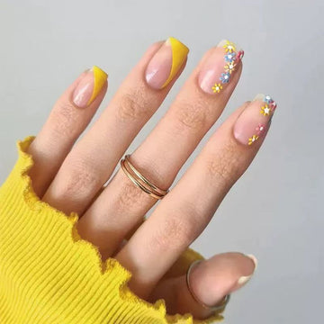Bright yellow French press-on nails with dainty floral accents.