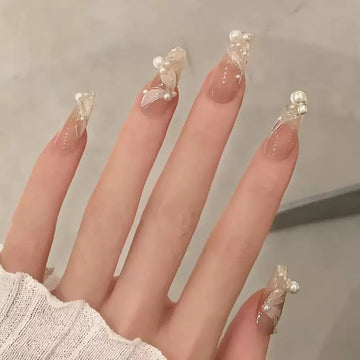 Nude stiletto nails with pearl and glitter decor