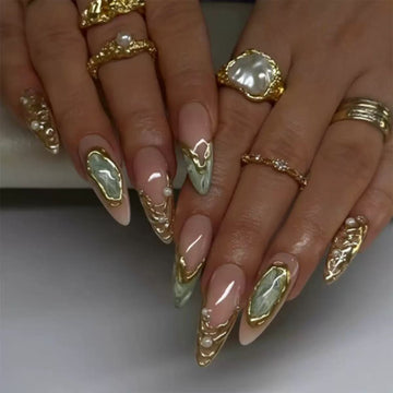 Nude stiletto nails with green glitter and gem decor